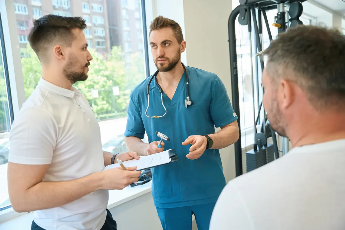 Two clinicians talking with a male patient
