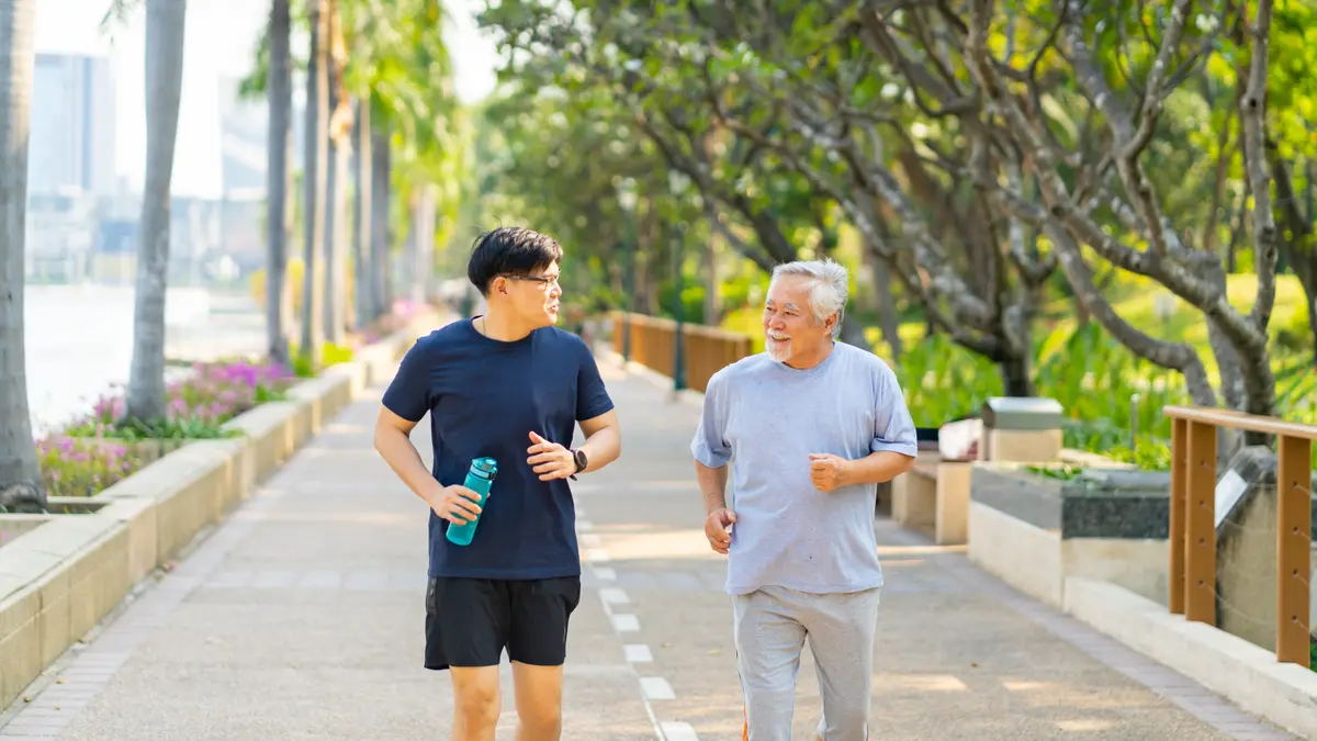 Younger and older man jogging together on a path